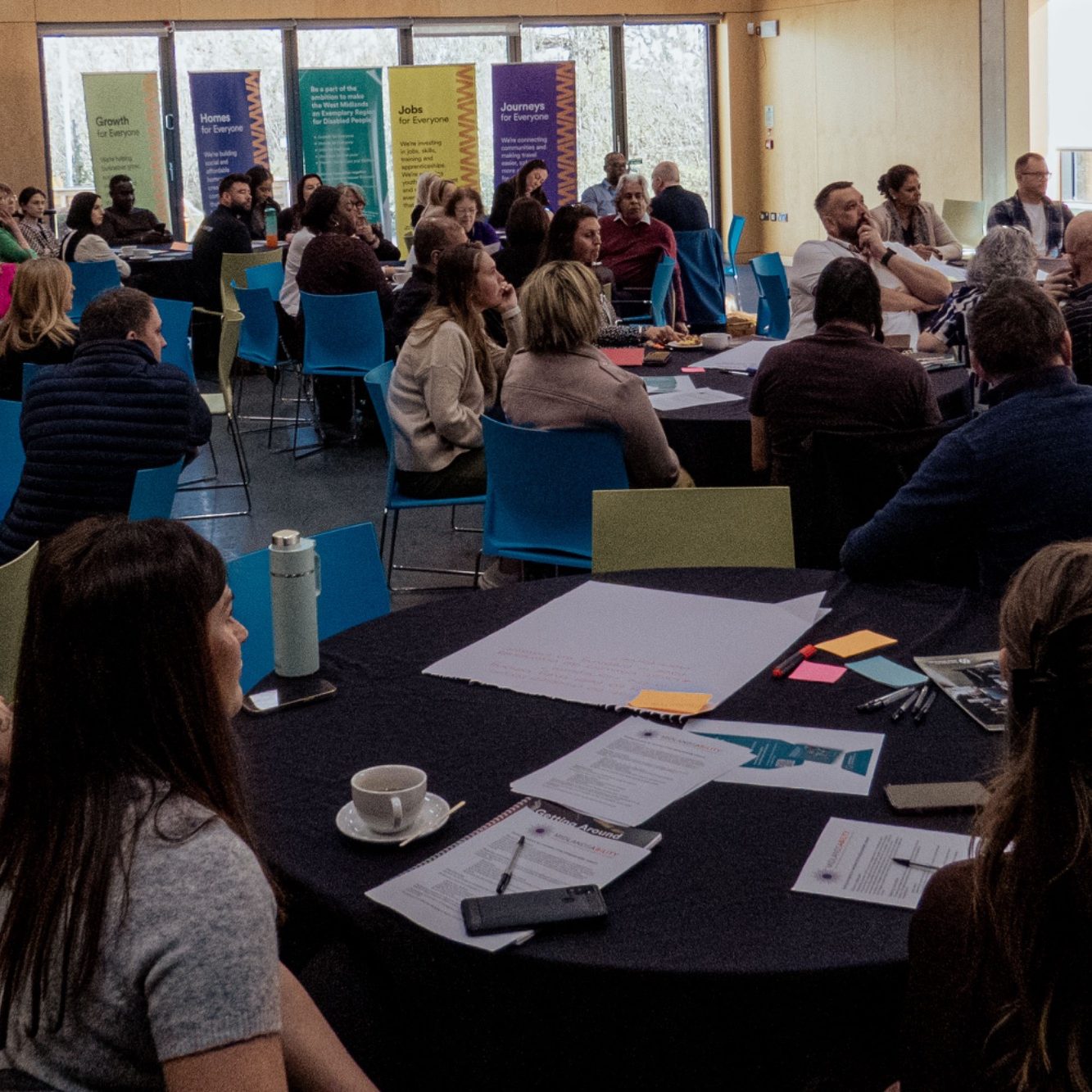 A group of people engaged in discussion around tables in a conference setting.