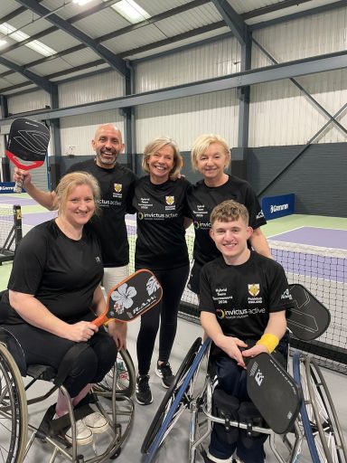 Team photo with two wheelchair players and three non-disabled players